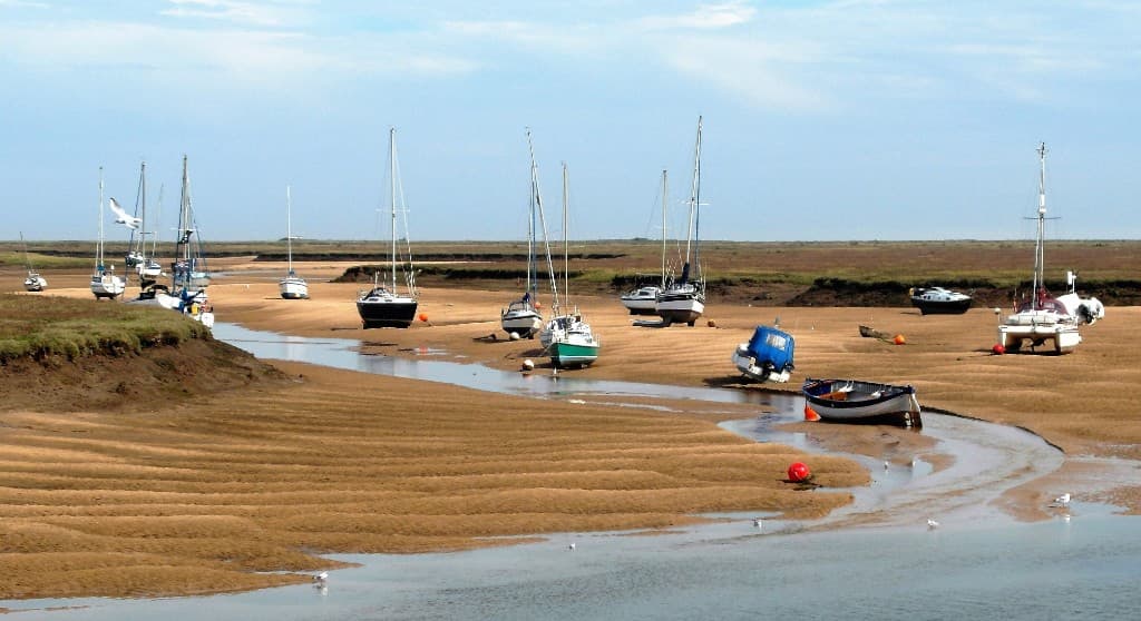 Boats resting on the sand at low tide in Wells-next-the-Sea harbour